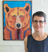 photo of CIO Tracy Schroeder standing near a colorful bear woodcut