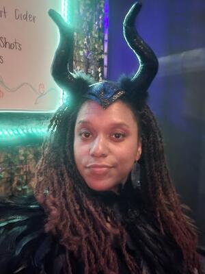 Jeané Blunt in costume as Maleficent, with a black feather collar and two black horns