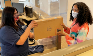 student receiving a Dell laptop from STEP staff